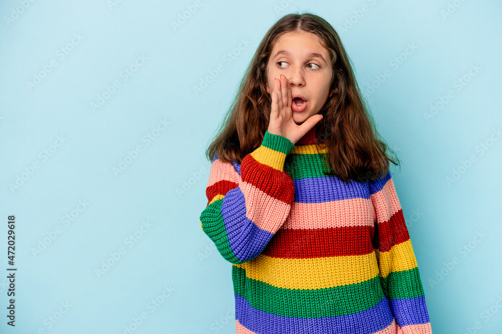 Little caucasian girl isolated on blue background is saying a secret hot braking news and looking aside Little caucasian girl isolated on blue background is saying a secret hot braking news and looking aside