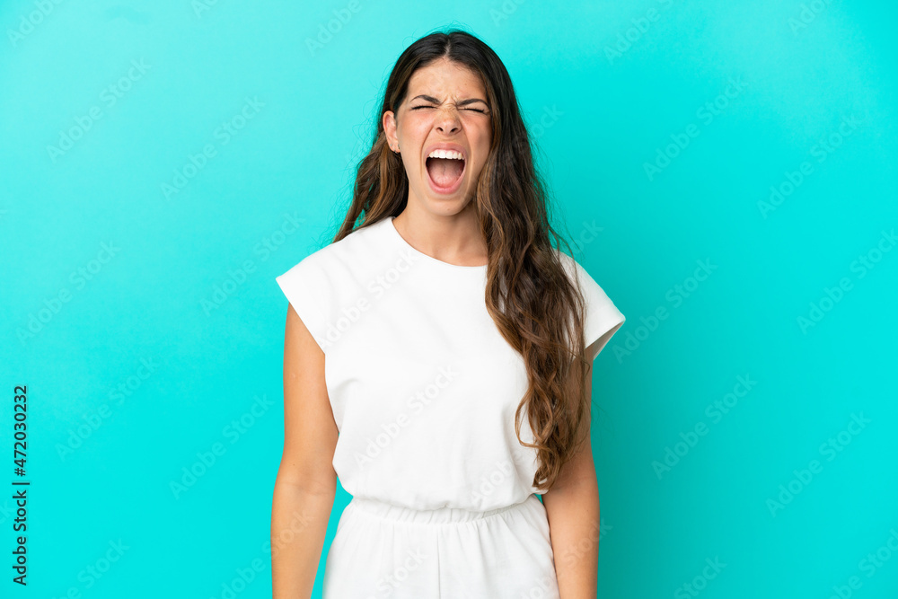Young caucasian woman isolated on blue background shouting to the front with mouth wide open Young caucasian woman isolated on blue background shouting to the front with mouth wide open