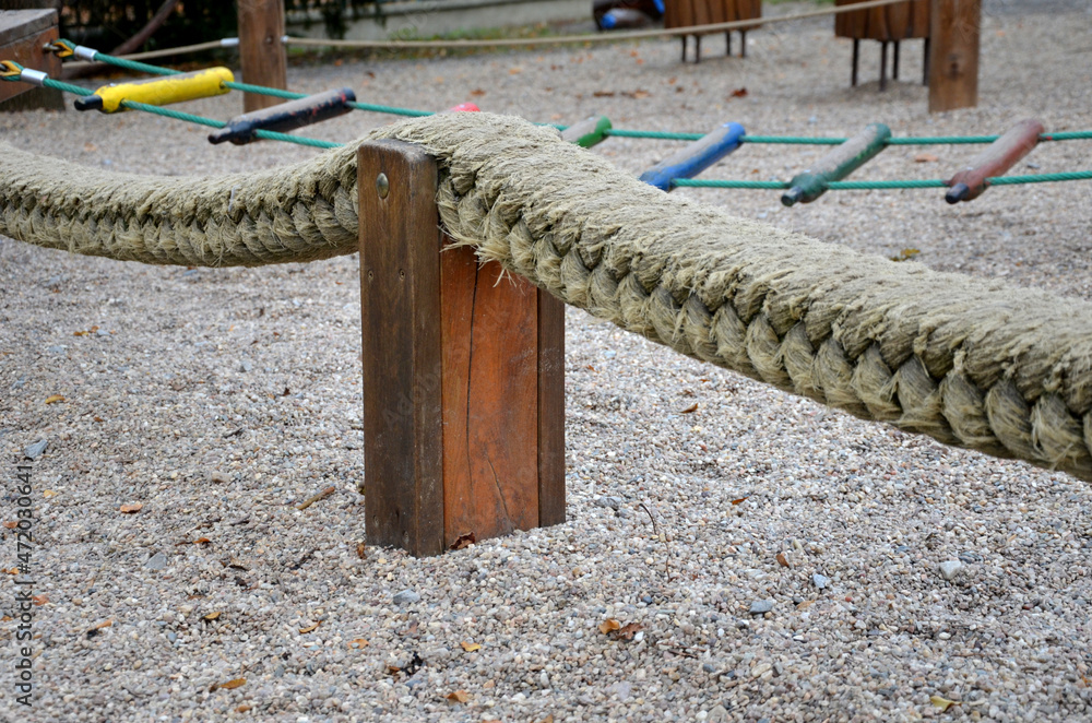 Fototapeta premium playground with colorful rope ladders stretched low above the ground between several pillars. the child tries to walk like a balance beam over awkward obstacles. may fall with sand or pebbles