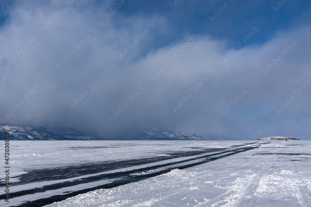 Winter road on the ice of Lake Baikal near Olkhon Island on a cloudy day