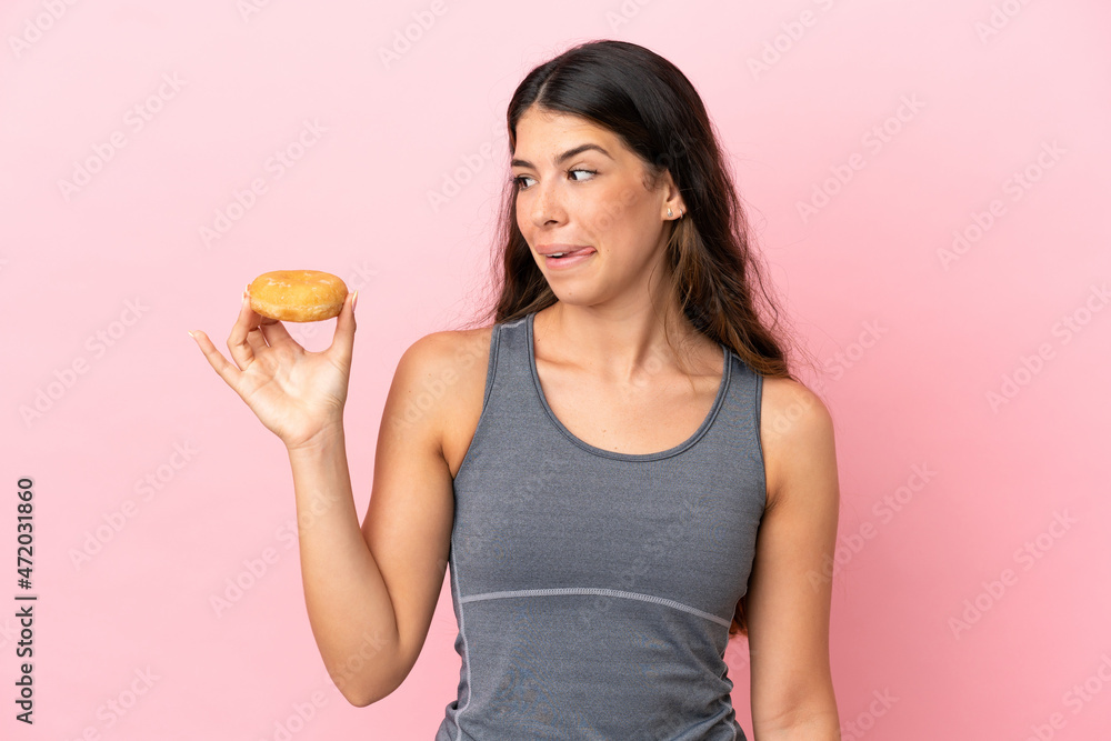 Young caucasian woman isolated on pink background holding a donut Young caucasian woman isolated on pink background holding a donut