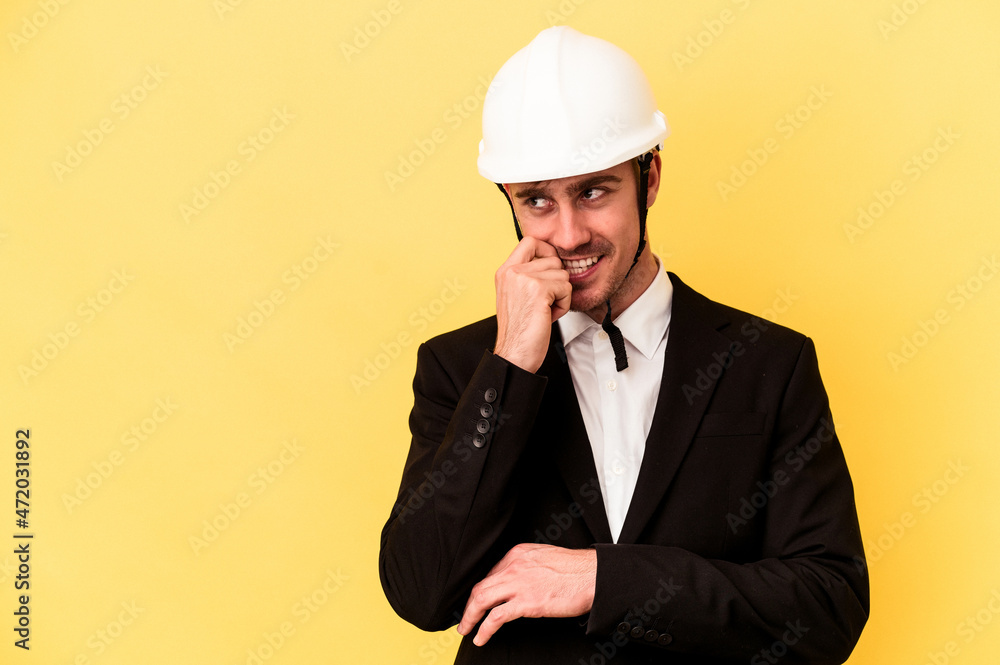 Young architect caucasian man isolated on yellow background relaxed thinking about something looking at a copy space. Young architect caucasian man isolated on yellow background relaxed thinking about something looking at a copy space.