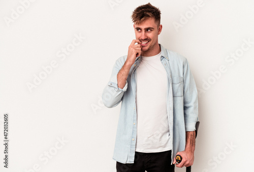 Young caucasian man holding crutch isolated on white background relaxed thinking about something looking at a copy space. photo