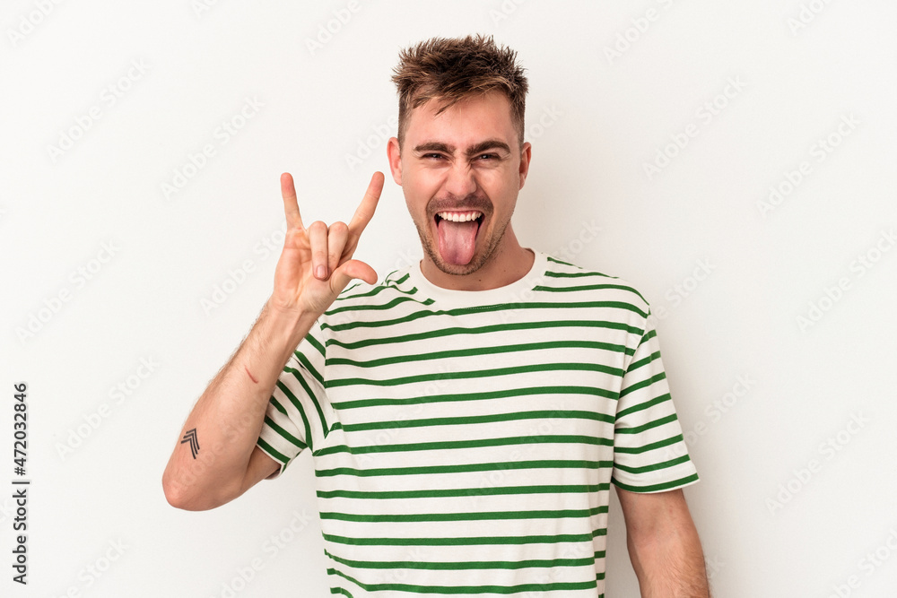 Young caucasian man isolated on white background showing a horns gesture as a revolution concept. Young caucasian man isolated on white background showing a horns gesture as a revolution concept.