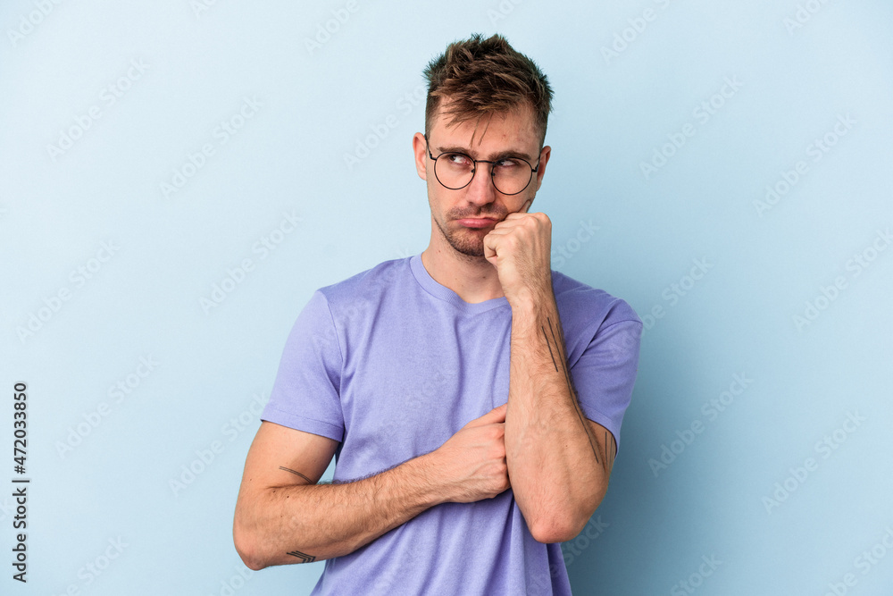 Young caucasian man isolated on blue background thinking and looking up, being reflective, contemplating, having a fantasy. Young caucasian man isolated on blue background thinking and looking up, being reflective, contemplating, having a fantasy.