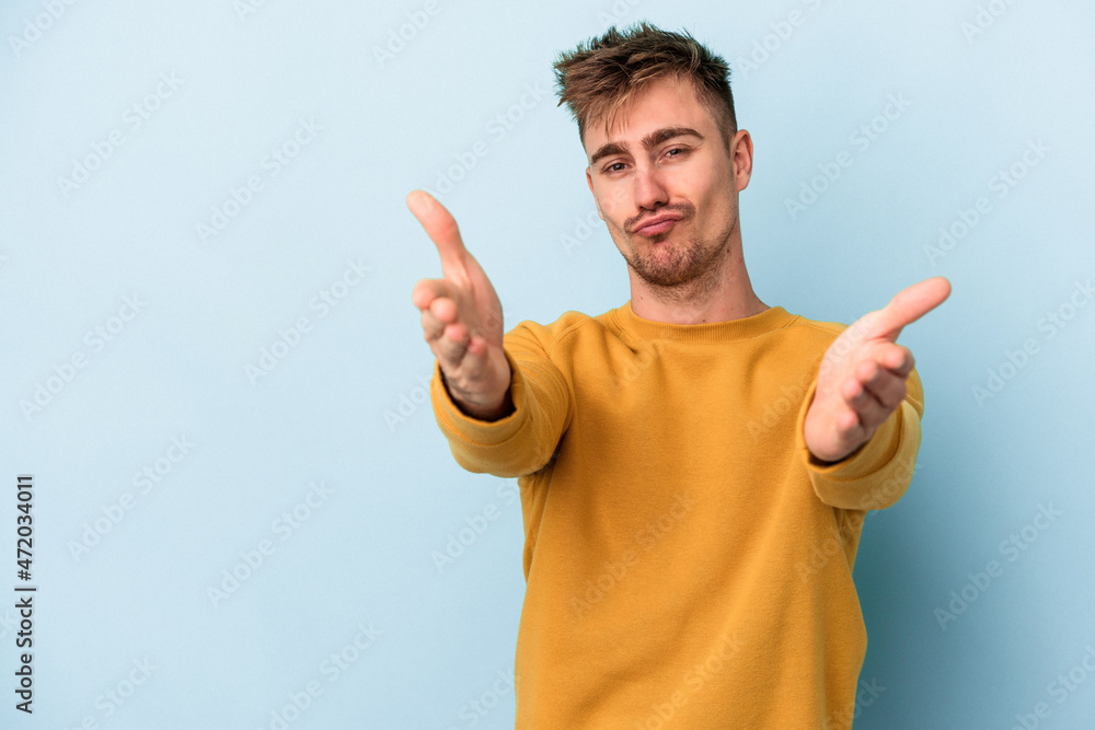 Young caucasian man isolated on blue background folding lips and holding palms to send air kiss. Young caucasian man isolated on blue background folding lips and holding palms to send air kiss.