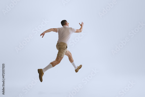 Dynamic portrait of young man dressed in 50s  60s style running away isolated on white background. Retro vintage style