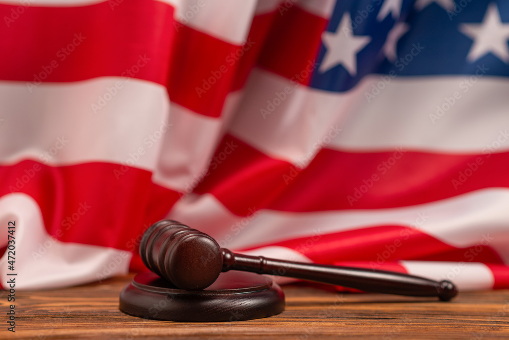 Wooden judge gavel and soundboard on american flag background.