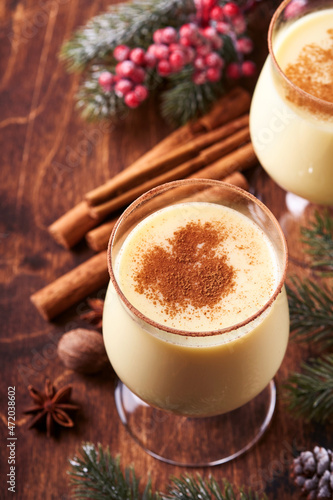 Eggnog Christmas. Delicious winter cocktail milk, rum and cinnamon served in two glasses with shortbread star shape sugar cookies, fir branch over white wooden plank table. Close up. Mock up.