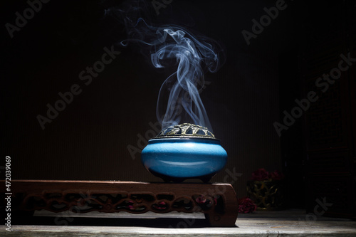 Smoke from burning incense sticks standing on lotus incense holder