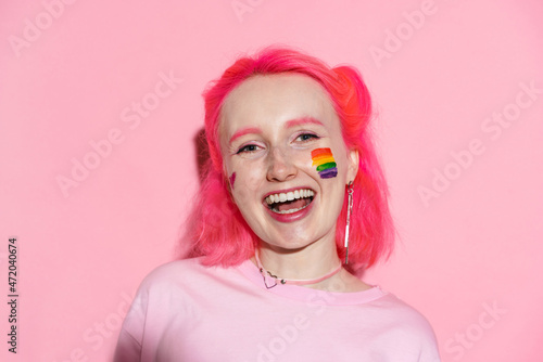 Young woman with rainbow makeup laughing and looking at camera