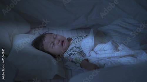 asian baby infant face sad mood and crying on bed at night.