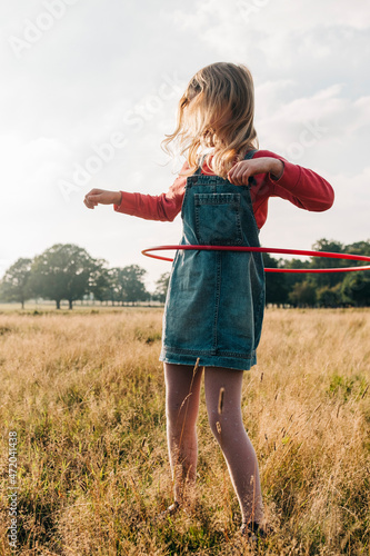Girl playing with hula hoop in park at weekend photo