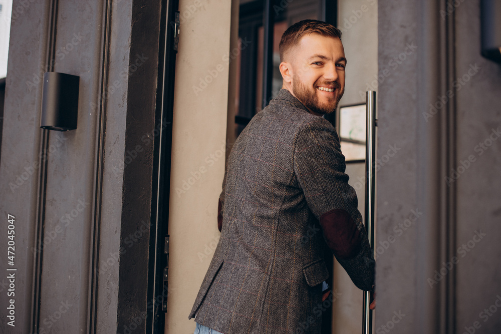 Man smiling and opening doors into a cafe Man smiling and opening doors into a cafe