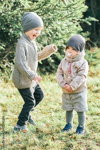 Outdoor portrait of little preschool brother trying to cheer up shy toddler sister © annanahabed