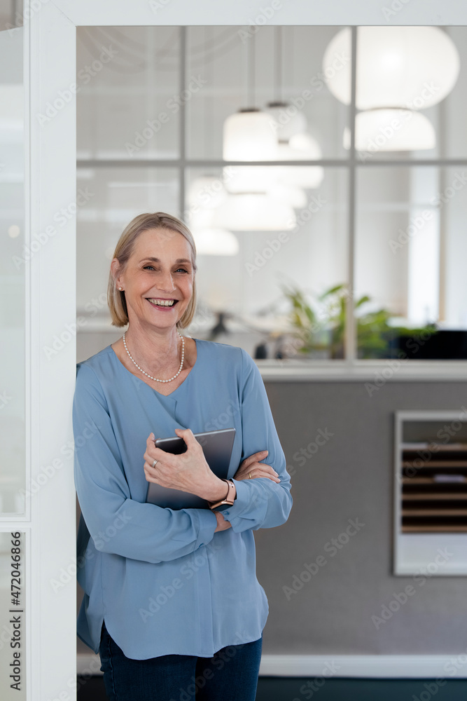 Businesswoman holding tablet PC at office doorway Businesswoman holding tablet PC at office doorway