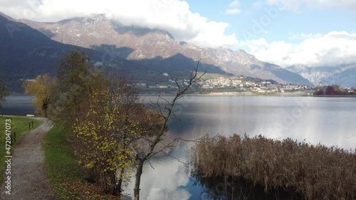 Aerial view of an alpine lake and the surrounding mountains and vegetations reflected on a cloudy day, Brianza, Lombardy, Italy