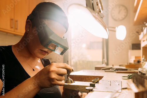 Female jeweler positioning diamond in ring at workshop photo