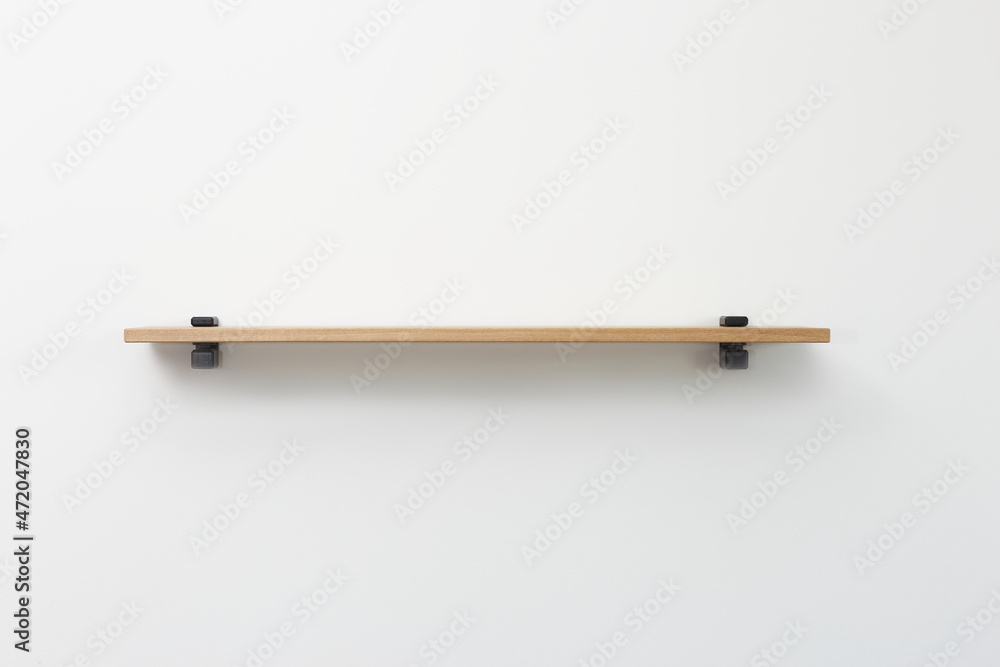 straight view of wooden shelf with black bracing over white wall background. straight view of wooden shelf with black bracing over white wall background.
