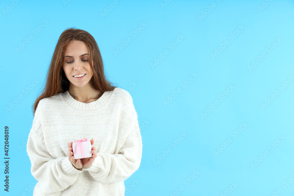 Attractive woman holds gift box on blue background Attractive woman holds gift box on blue background
