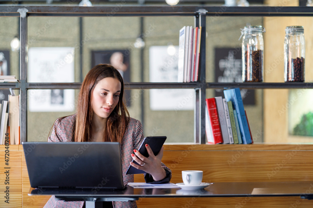 Young businesswoman with laptop using smart phone in cafe Young businesswoman with laptop using smart phone in cafe