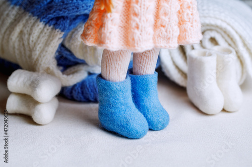 Handmade wool felt boots on the doll's feet. Traditional home handicrafts made from natural materials in winter. Hobby for adults and children.