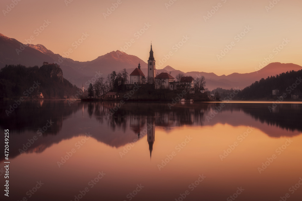 Picturesque sunrise on the lake Bled. Perfect reflection of the church in smooth water. Atmospheric mood. Nature background. The nature of Slovenia. Lake Bled.Parish Church of St. Martina. Europe Picturesque sunrise on the lake Bled. Perfect reflection of the church in smooth water. Atmospheric mood. Nature background. The nature of Slovenia. Lake Bled.Parish Church of St. Martina. Europe