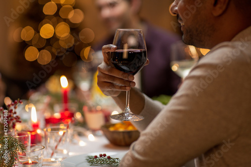 holidays, party and celebration concept - close up of happy smiling man having christmas dinner at home and drinking red wine