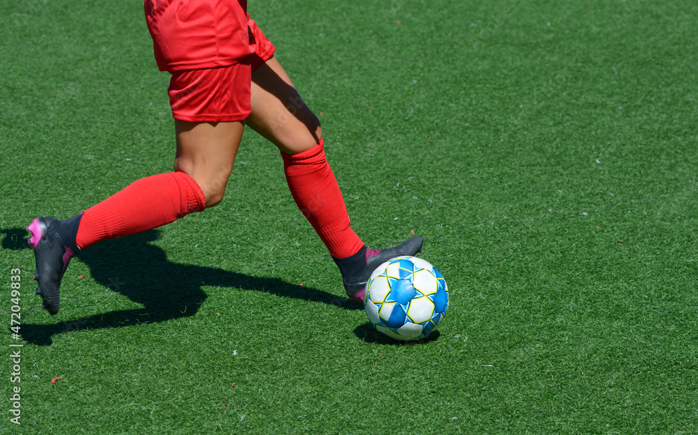 Woman football player kicking ball on a soccer field Woman football player kicking ball on a soccer field