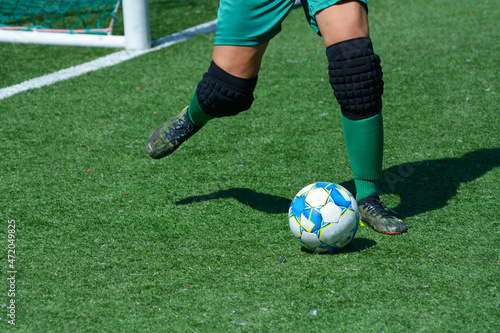 Fototapeta Naklejka Na Ścianę i Meble -  Woman goalkeeper kicking ball in front of a football goal on a soccer field