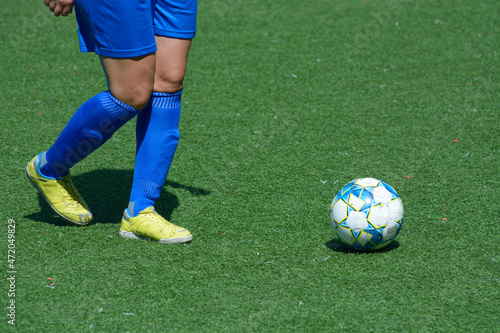 Woman football player kicking ball on a soccer field © Yurii Zushchyk