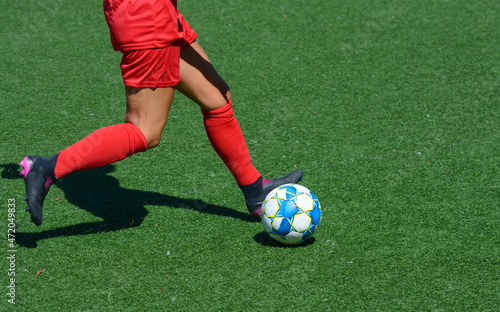 Woman football player kicking ball on a soccer field