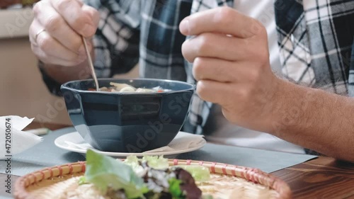 A man is stirring a ready-made noodle soup and seasonings in a plate while sitting in a restaurant. The concept of Vietnamese cuisine. Hands of a man in close-up.
