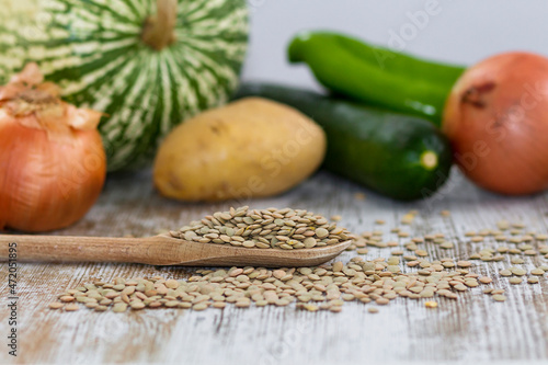Raw lentils and vegetables over a wooden table photo
