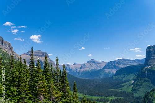 View from Logan Pass in Glacier National Park, Montana on a sunny summer day, with glacial valley, snow-capped mountains, alpine lakes, and grass photo