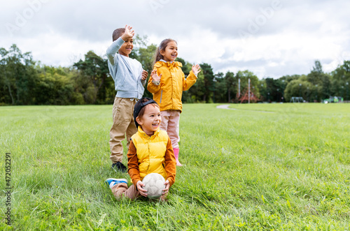 childhood, leisure and people concept - group of happy children with soccer ball at park
