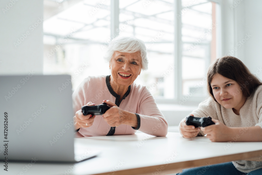 Senior woman playing video game with girl at home Senior woman playing video game with girl at home