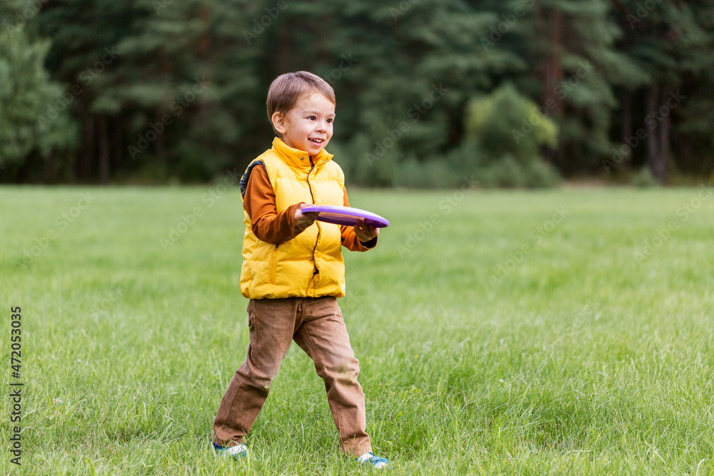 childhood, leisure and people concept - happy little boy playing game with flying disc at park childhood, leisure and people concept - happy little boy playing game with flying disc at park