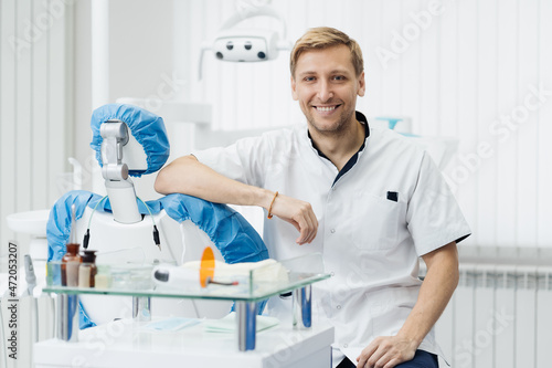 Portrait of a positive young male dentist in uniform at the dental office