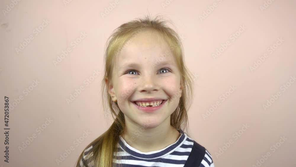 A beautiful five-six-year-old girl shows her mouth with fallen milk teeth.She smiles and grimaces. A beautiful five-six-year-old girl shows her mouth with fallen milk teeth.She smiles and grimaces.