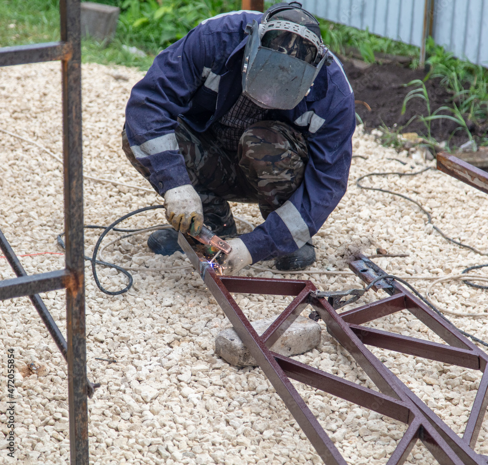 A worker welds metal at a construction site. A worker welds metal at a construction site.