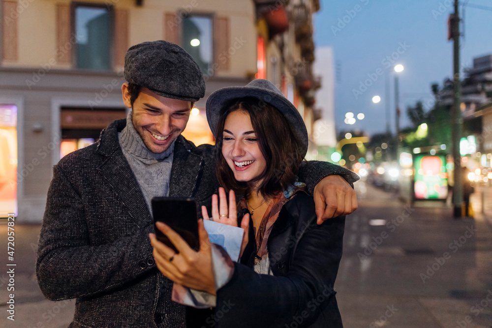 Happy young couple waving on video call through smart phone in city Happy young couple waving on video call through smart phone in city