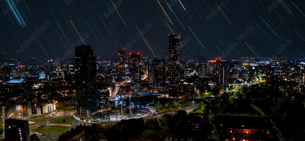 Aerial shot of Manchester, UK at night. Night skyscrapers standing in the city lights with a magical night sky with long exposure stars. Aerial shot of Manchester, UK at night. Night skyscrapers standing in the city lights with a magical night sky with long exposure stars.