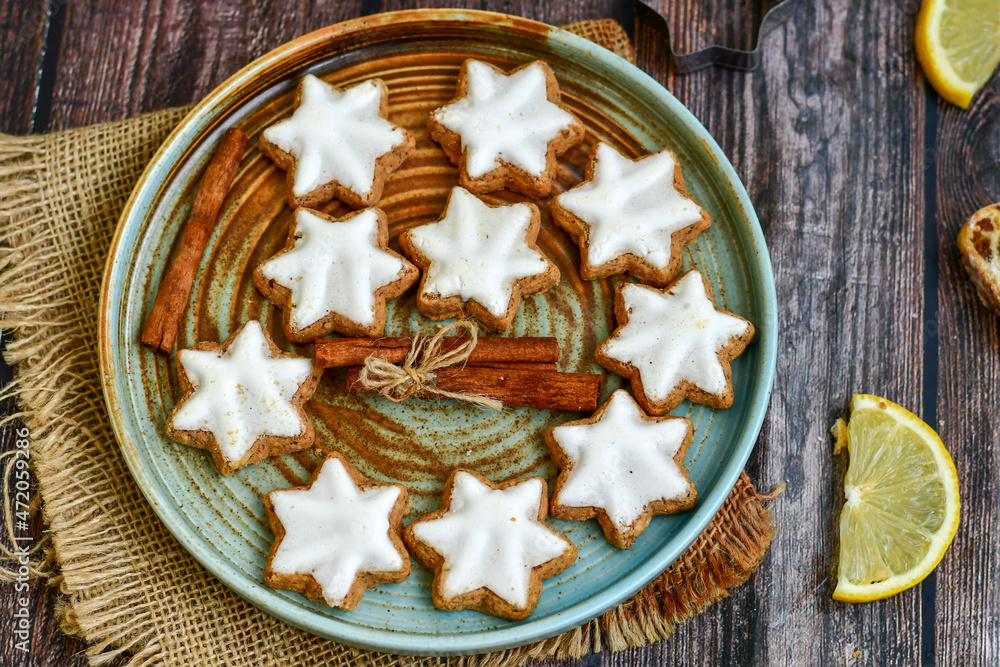 Gingerbread star shaped cookies and cinnamon sticks on wooden background with lights . Christmas card background . Holiday wallpaper Gingerbread star shaped cookies and cinnamon sticks on wooden background with lights . Christmas card background . Holiday wallpaper