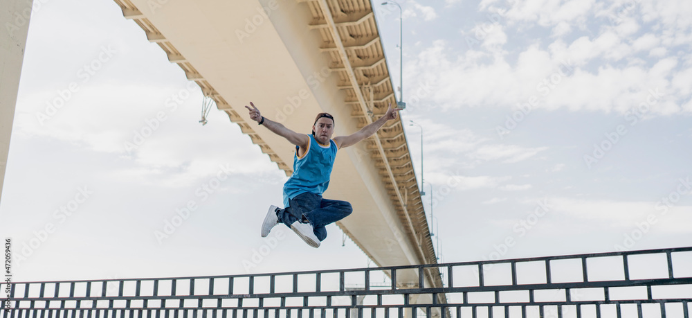 Naklejka premium young person in jumping motion outdoors flying in the air, dancer doing acrobatic moves