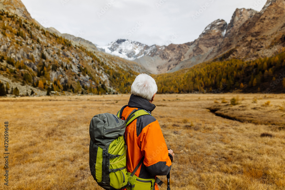 Senior backpacker looking at mountains at Rhaetian Alps, Italy Senior backpacker looking at mountains at Rhaetian Alps, Italy
