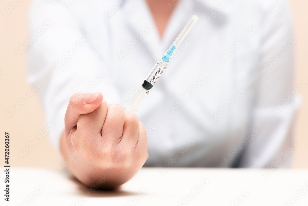 Doctor is shaking by her fist with a syringe with the anesthetic close up. Doctor is shaking by her fist with a syringe with the anesthetic close up.