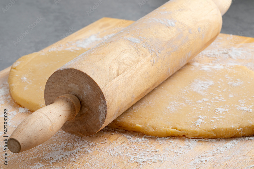 Preparing fresh dough for baking with a wooden rolling pin and flour close up Preparing fresh dough for baking with a wooden rolling pin and flour close up