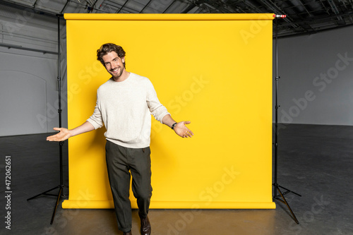 Handsome businessman gesturing in front of yellow backdrop photo
