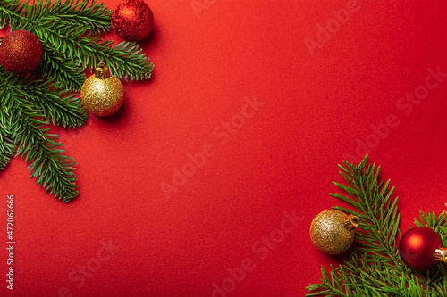 Christmas decorations and fir tree branch on red background